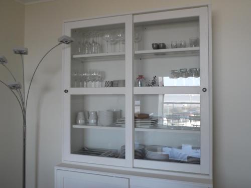 a white cabinet filled with plates and dishes at RESIDENCE LES BARGES in Saint-Jean-de-Monts