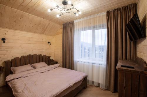 een slaapkamer met een bed en een groot raam bij Майя in Mykulychyn
