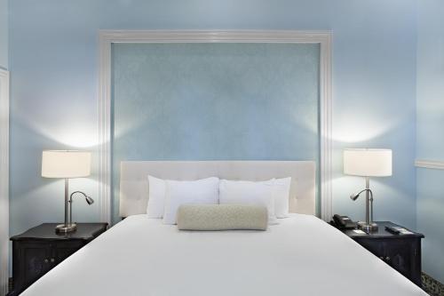 a bedroom with a large white bed with two lamps at Hotel la Perla Leon in León