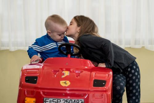 a woman kissing a baby in a red toy car at SPA Hotel Medicus in Varshets