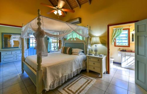 a bedroom with a canopy bed and a bathroom at Casa Chiesa in English Harbour Town