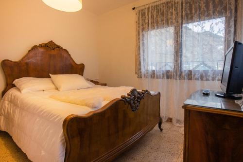 1 dormitorio con 1 cama y escritorio con TV en JAT Mountain Houses - Casa Agustí 3er pis - Cèntric, al costat del Telecabina de Canillo en Canillo
