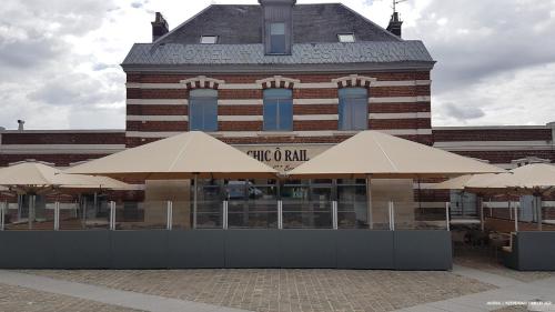 a building with tan umbrellas in front of it at Chic'o Rail in Saint-Omer