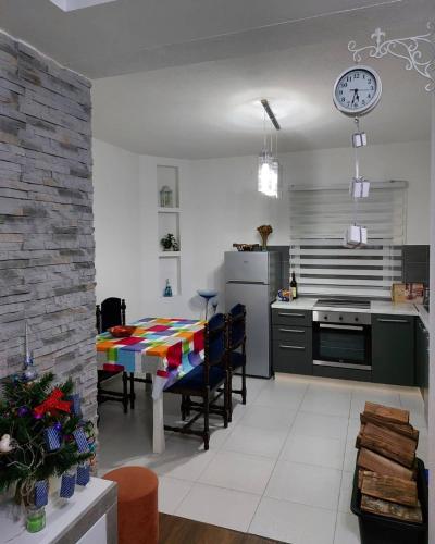 a kitchen and dining room with a table and a clock at Guest house Vlahovic in Kolašin