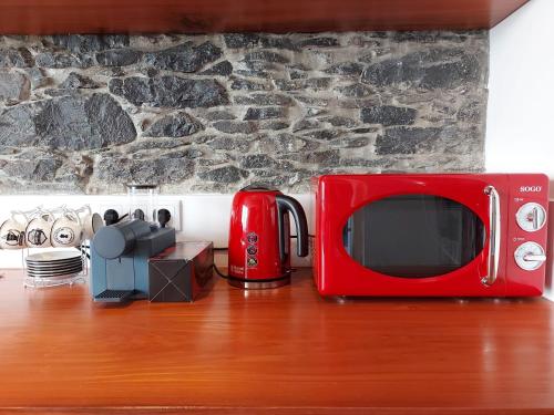 a red microwave sitting on top of a wooden table at CASA DO SOL in Jardim do Mar