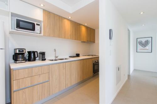 a kitchen with wooden cabinets and a microwave at Austral Departamentos in Ushuaia