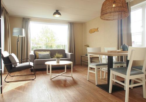 a living room with a couch and a table at Chaletparc Krabbenkreek Zeeland - Chalet 154 in Sint Annaland