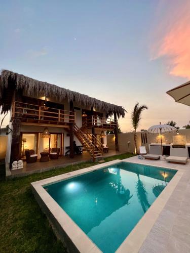 a villa with a swimming pool in front of a house at Casa Bali Vichayito in Vichayito