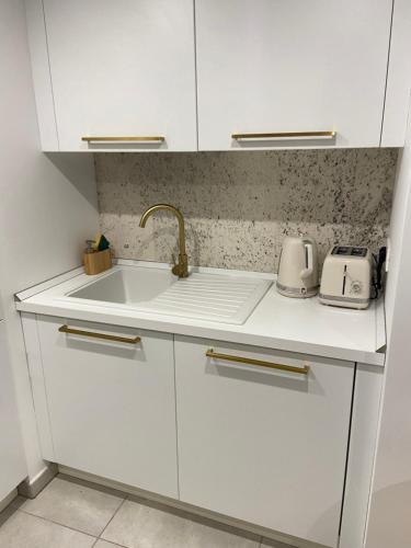 une cuisine avec des armoires blanches et un évier dans l'établissement 2 pièces avec terrasse et piscine cannes Croisette, à Cannes