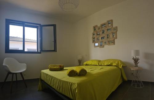 - une chambre avec un lit doté de draps jaunes et une fenêtre dans l'établissement Villa Cosy avec piscine privative, à Ghisonaccia