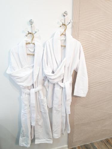 two white robes are hanging on a door at Suite Romantique in Hésingue