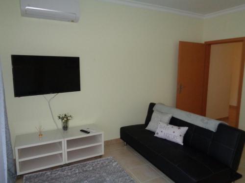 a living room with a black couch and a flat screen tv at Alto dos Navegantes in Armação de Pêra