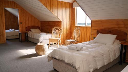 a bedroom with two beds and two chairs in it at Hotel Posada del Río - Chile Chico in Chile Chico