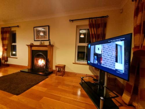 a living room with a television and a fireplace at Millstone Cottages in Milford