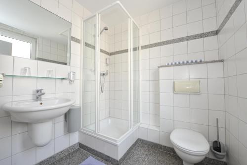 a white bathroom with a toilet and a sink at Insel Hotel in Cologne
