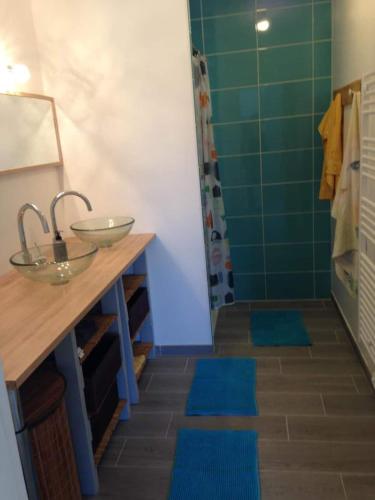 La salle de bains est pourvue d'un lavabo et d'une douche avec des tapis bleus. dans l'établissement Escapade a Chaucre - St Georges - Maison plain pied - 3 chambres - 7 couchages, à Chaucre