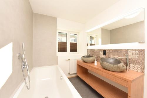 une salle de bains avec deux lavabos sur un comptoir en bois dans l'établissement Haller´s Posthaus, à Riezlern