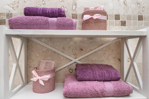 a shelf with three purple towels on it at DreamGarden Airport apartment & Secure parking & Airport shuttle in Iaşi