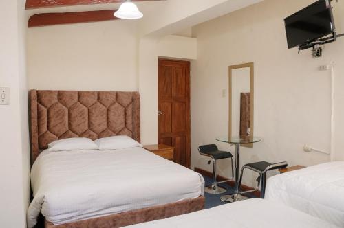 um quarto de hotel com duas camas e uma televisão em Hostal Chasky em Cusco