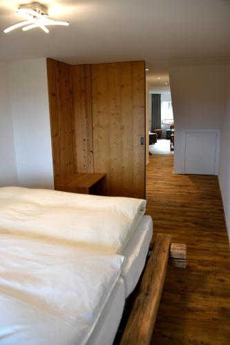 a bedroom with a large bed with a wooden wall at Hôtel de Ville in Gruyères