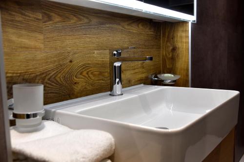 a white sink in a bathroom with a wooden wall at Hôtel de Ville in Gruyères