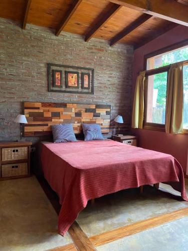 1 dormitorio con 1 cama grande con manta roja en Cabañas Los Castores en el Balneario Mar Azul