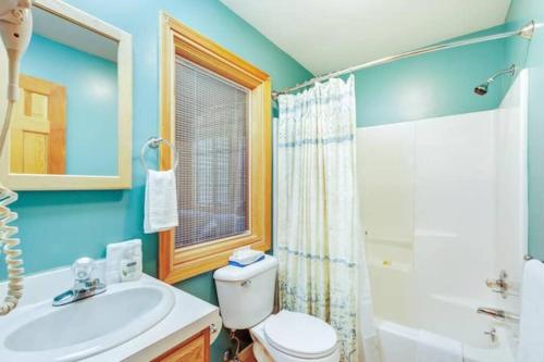 a bathroom with a white toilet and a sink at Secluded cabin on 10 acres - hot tub & game room! in Fennville