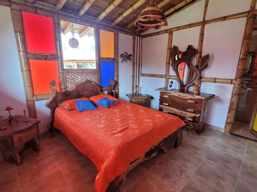 a bedroom with a bed with orange sheets and blue pillows at Chalet la texana in Filandia