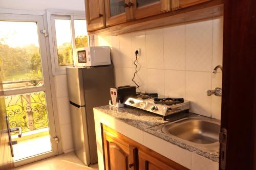 a kitchen with a stove and a sink and a window at Le Mas Provençal - Appartements in Yaoundé