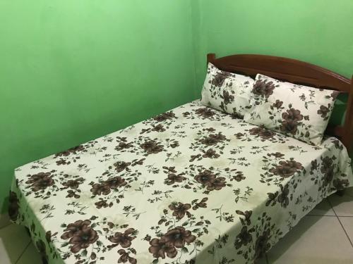 a bed with a white comforter with brown flowers on it at Casa Laranja in Vale do Capao