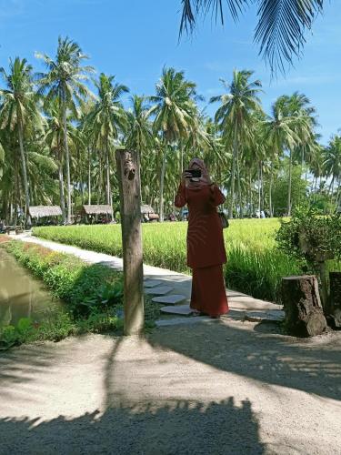 a woman taking a picture of a palm tree at Homestay Damai Sri Kota in Kepala Batas