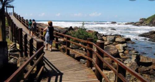 a group of people walking on a wooden bridge near the ocean at Casa Praia Temporada Itanhaém in Itanhaém