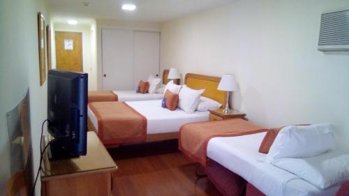 a hotel room with two beds and a flat screen tv at Hotel Presidente in Santiago