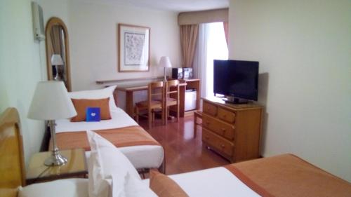 a hotel room with two beds and a flat screen tv at Hotel Presidente in Santiago
