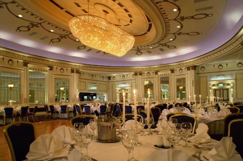 a banquet hall with white tables and chairs and a chandelier at The Midland Hotel in Bradford
