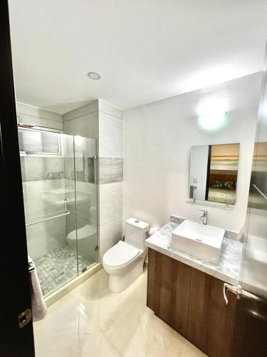 a bathroom with a toilet and a sink and a shower at Sunset View Malecón 1404 Vista panoramica al mar in Mazatlán