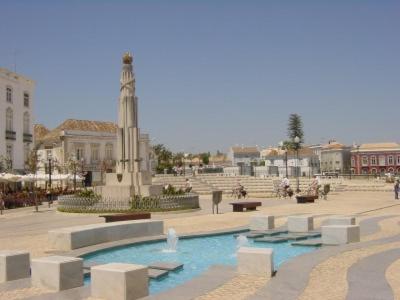 a courtyard with a fountain and a clock tower at Taah Billa Guest House in Tavira