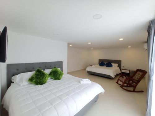 a bedroom with a white bed with two green pillows at Hotel Santa Lucia in Socorro
