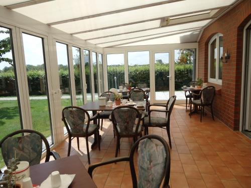 a screened porch with tables and chairs and windows at Hotel Marianne und Restaurant Kiek In in Plau am See