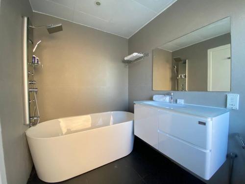 a bathroom with a tub and a sink and a mirror at Luxury JBR Apartments , beach , pool , parking in Dubai