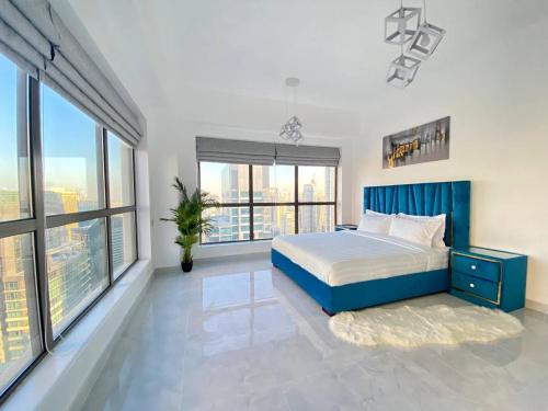a bedroom with a blue bed and large windows at Luxury JBR Apartments , beach , pool , parking in Dubai
