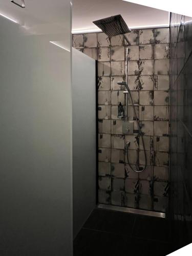 a shower in a bathroom with a tile wall at The Kepos Hotel Erlangen in Erlangen