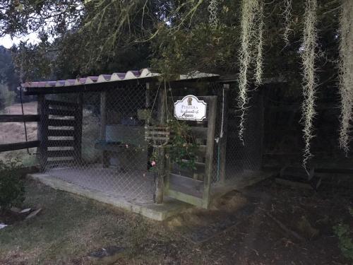 a small building with a sign on it under a tree at Acogedora cabaña de madera en la naturaleza para desconectarse in Sogamoso