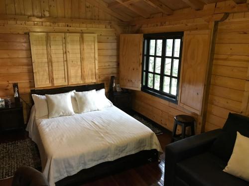 ein Schlafzimmer mit einem Bett in einem Blockhaus in der Unterkunft Acogedora cabaña de madera en la naturaleza para desconectarse in Sogamoso