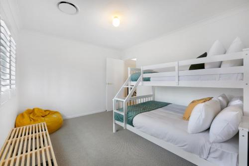 a white bedroom with a bunk bed and a ladder at Mediterranean Surfers Paradise Townhouse with BBQ in Gold Coast