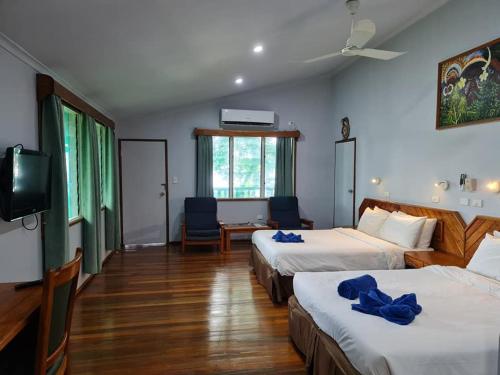 a hotel room with two beds and a flat screen tv at Tawali Leisure & Dive Resort in Alotau