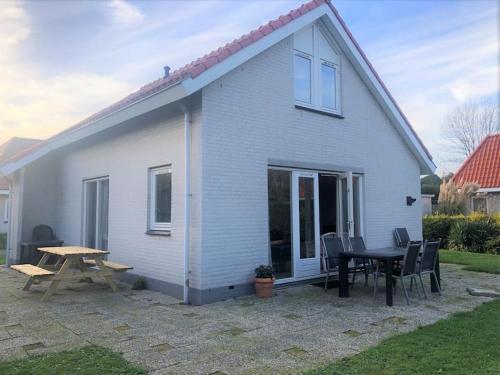 Casa blanca con mesa y mesa de picnic en Strand Villa Stern Noordwijk, en Noordwijk