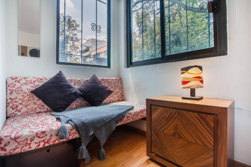 a living room with a couch and two windows at Nomadier Experience Mexico City Condesa in Mexico City