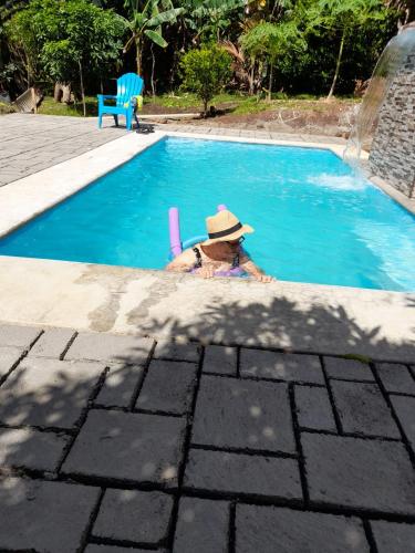 a man in a swimming pool with a hat in the water at Agutipaca Bungalows in Bagaces