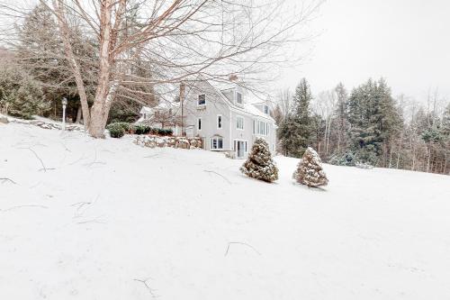 two christmas trees in the snow in front of a house at Campton White Mountains Retreat in Campton